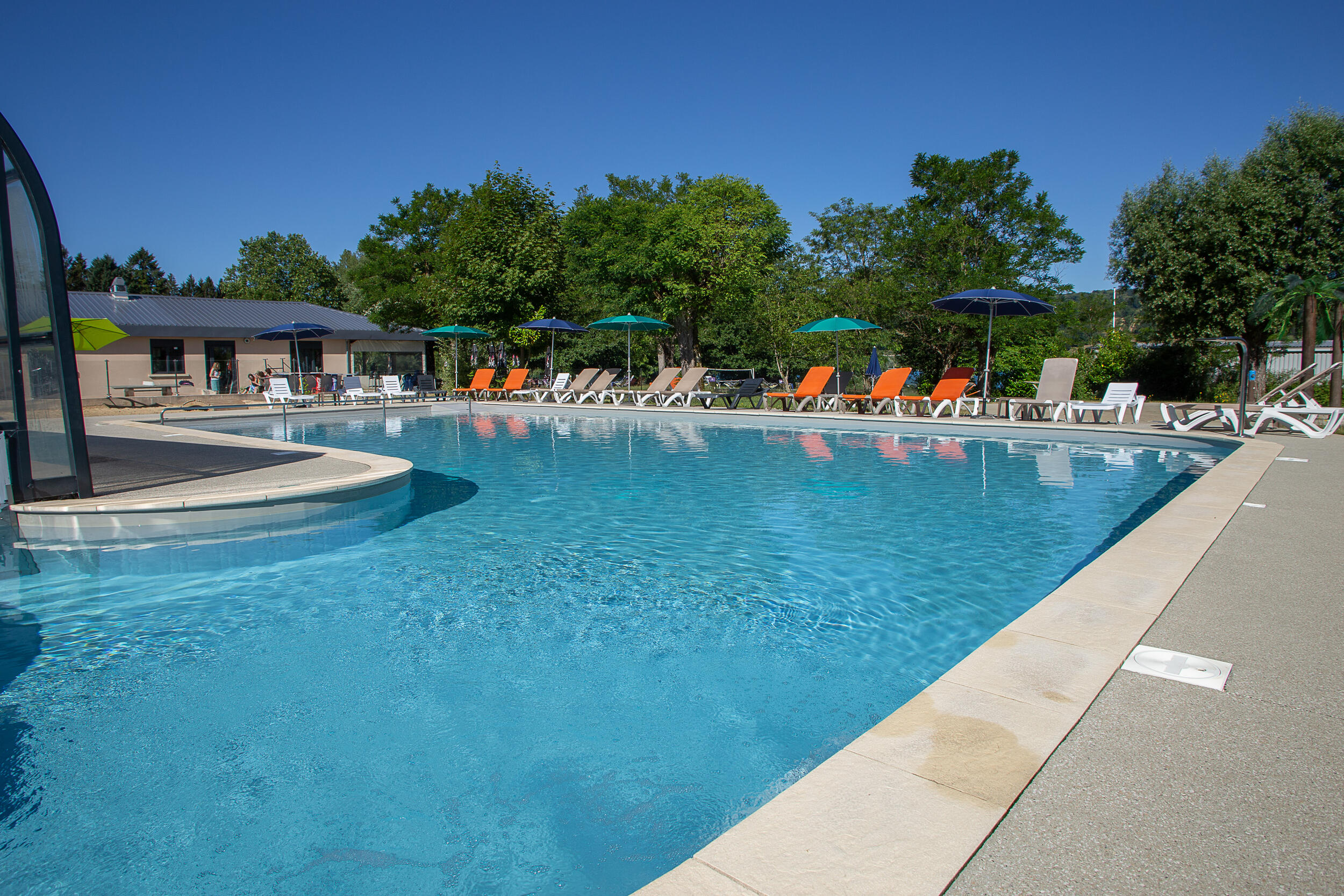 Bassin extérieur de la piscine du camping au lac de Paladru en Isère, transats et parasols